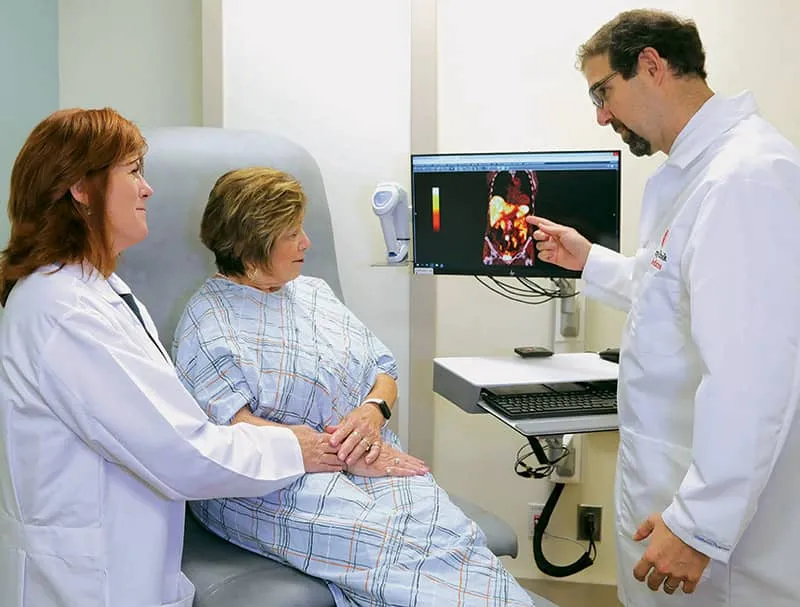 Dr. Aaron Sasson discusses scan results with patient and another medical professional in an exam room.
